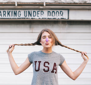 Teen girl wearing lavender Noz tinted sunblock on her nose, blowing a kiss and playfully posing and pulling her pigtails