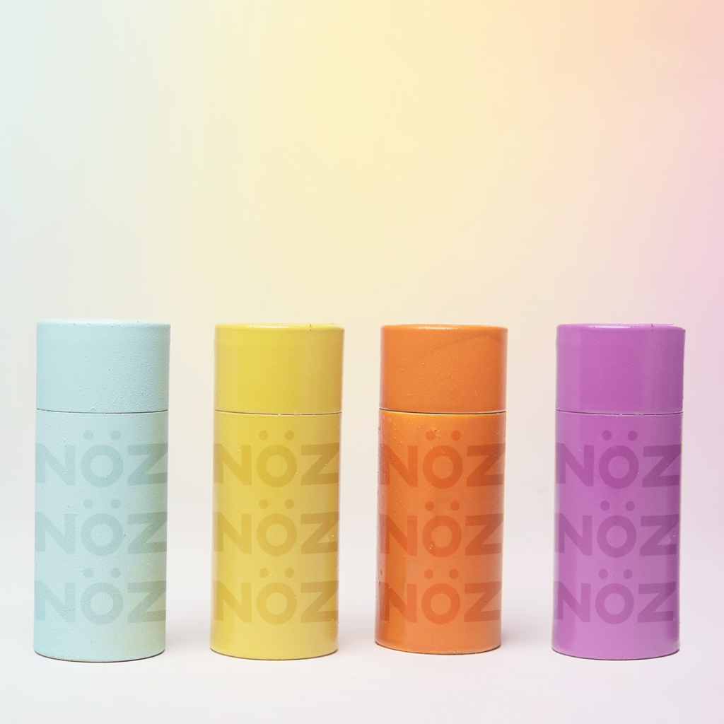 Noz reef safe, vegan, & cruelty free sunscreen bottles lined up next to each other in seafoam, amber, orange, & lavender