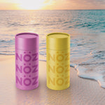 Load image into Gallery viewer, Two Noz reef safe sunscreen on the beach at sunset in the sand with waves lapping at the bottom edge of the sun cream bottles
